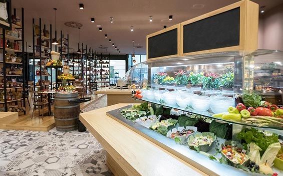 L'intérieur d'un marché alimentaire avec un bar à salades, des produits frais et des étagères remplies de marchandises.