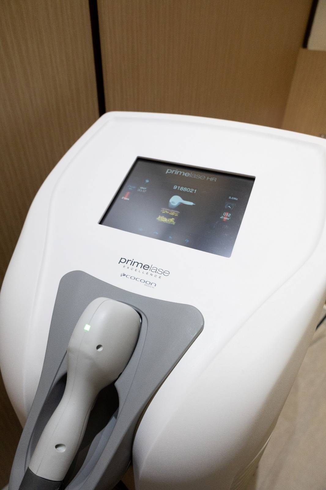 Mano sosteniendo un implante dental con una corona de cerámica blanca sobre un tornillo de plata.