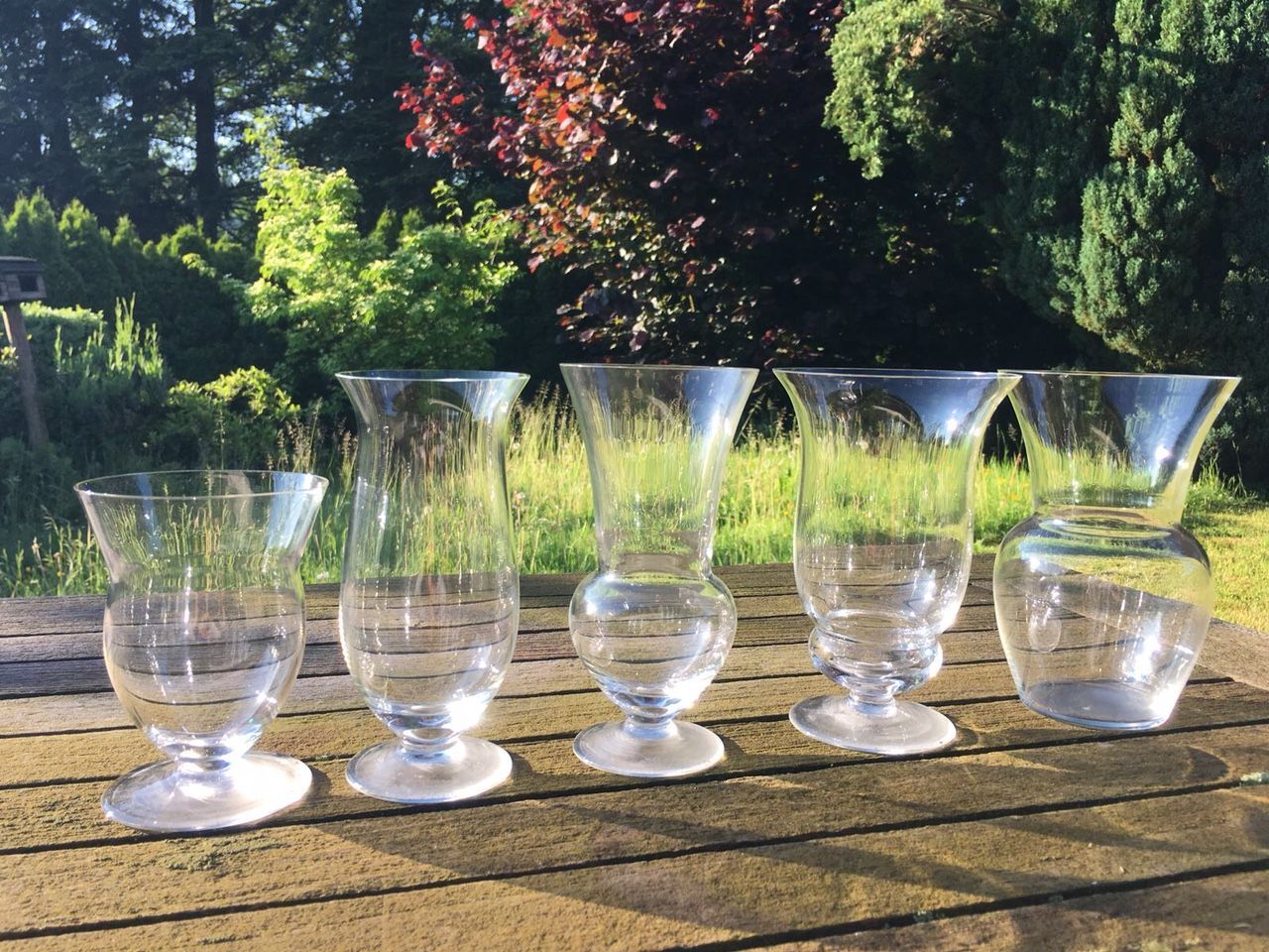 Filigranes Glasset mit schwungvollen Formen auf einem Tisch aus Massivholz angeordnet.