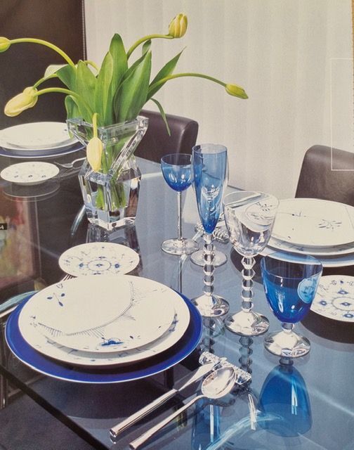 Edles Tischarrangement mit kunstvoller Besteckanordnung, Kristallgläsern und frischen Blumen als Zentrum.