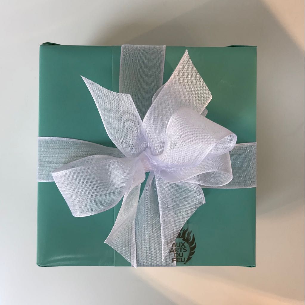 Stilvoll verpacktes Geschenk mit eleganter Schleife und handgeschriebener Karte in sanften Pastelltönen.