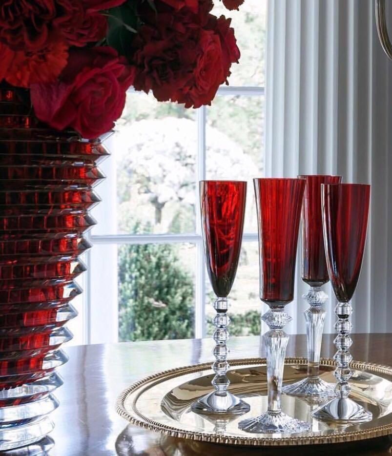 Vier gefüllte Weingläser auf einem festlich gedeckten Tablett, neben einer teilweise sichtbaren Vase.