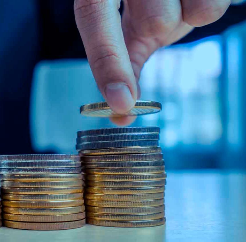 Una persona está colocando una moneda encima de una pila de monedas.