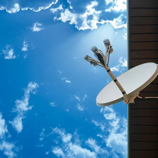 Una antena parabólica en una pared con un cielo azul de fondo