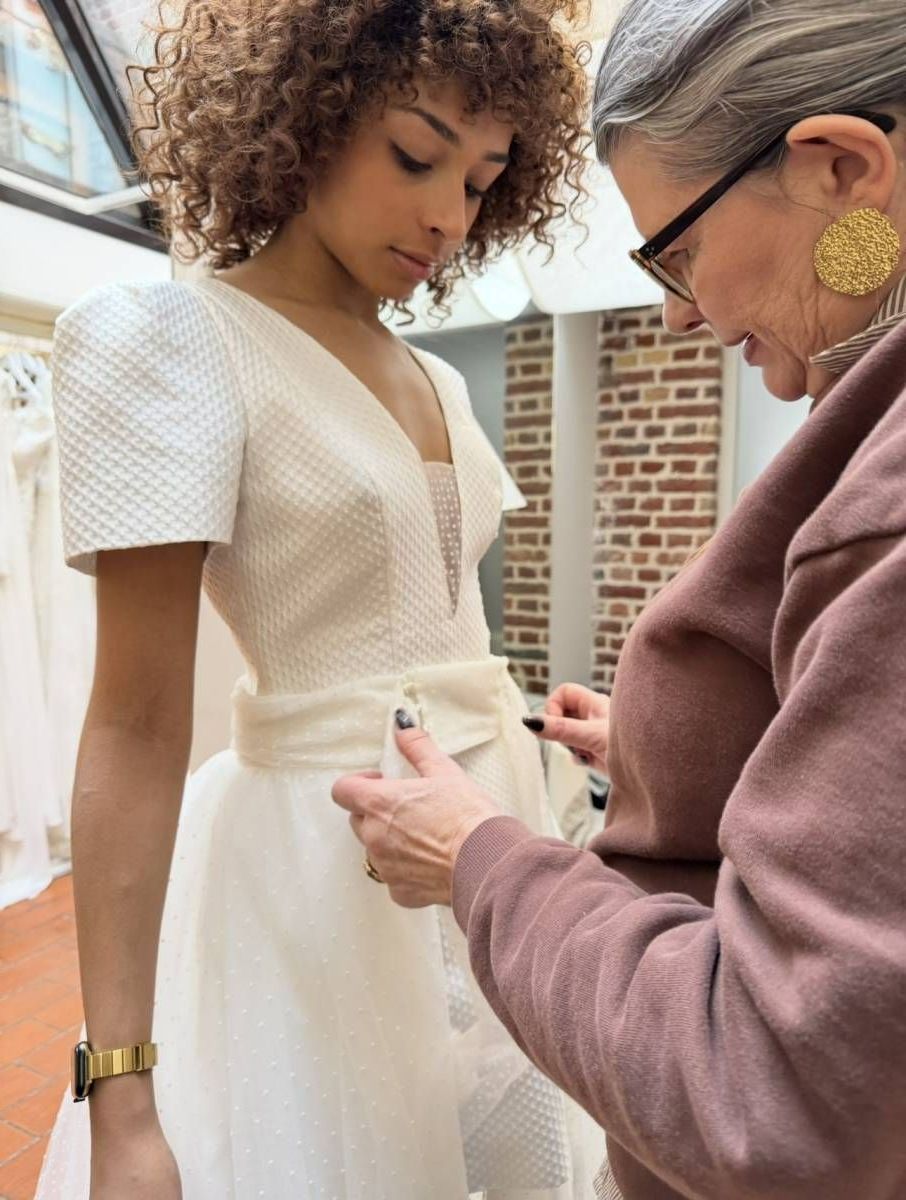 Une femme ajuste la taille d'une robe de mariée