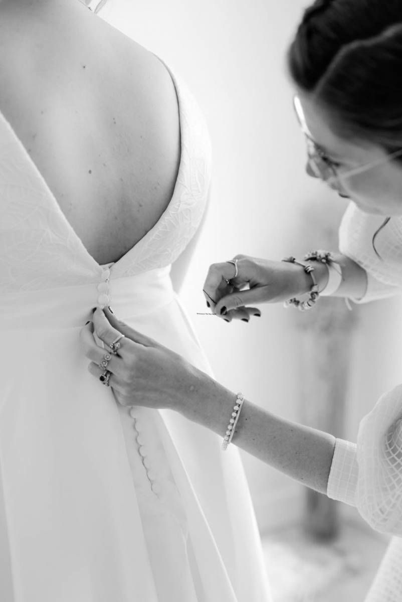 Une couturière ajuste le dos d'une robe