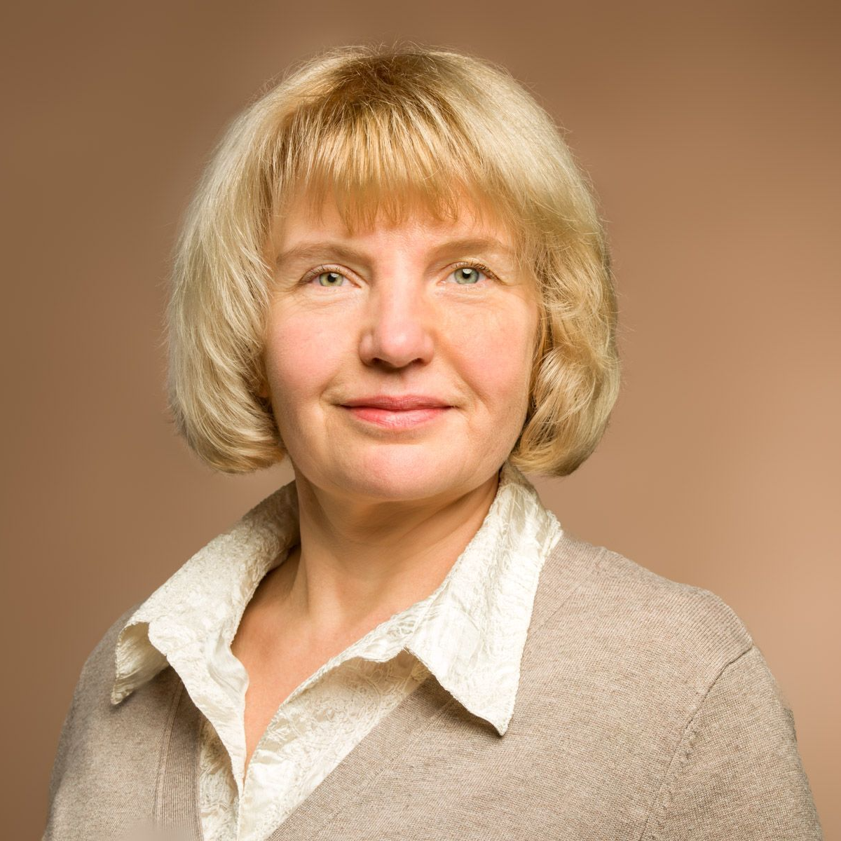 Eine Frau mit blonden Haaren trägt einen Pullover und ein weißes Hemd.