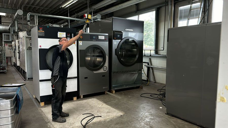Ein Mann steht vor einer Reihe von Waschmaschinen in einer Waschküche.