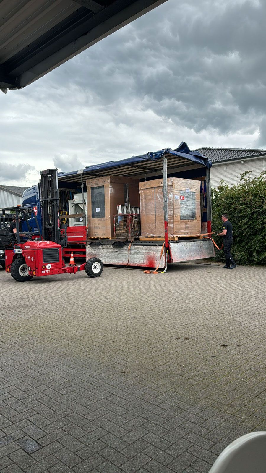 Ein Gabelstapler belädt einen LKW mit Kisten auf einem Anhänger.