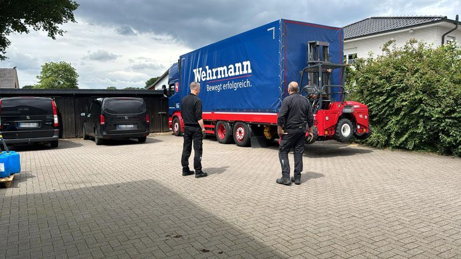 Zwei Männer stehen vor einem großen blauen Lastwagen.