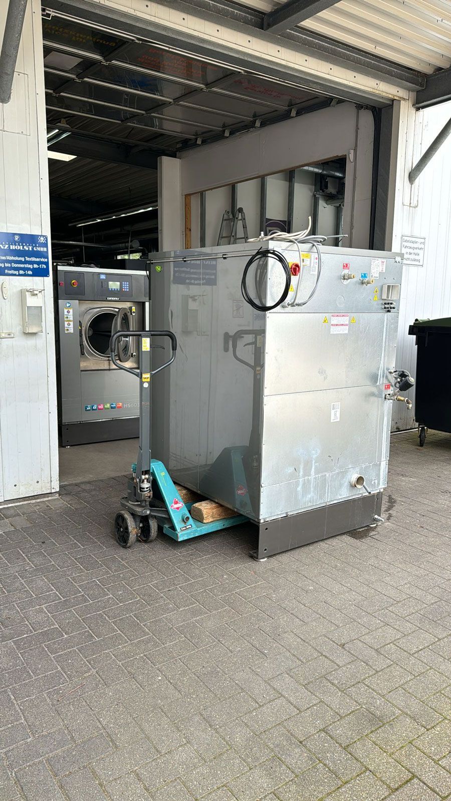 Eine Waschmaschine wird mit einem Hubwagen in eine Garage geladen.