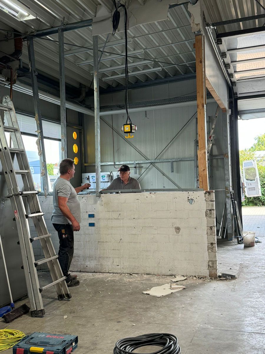 Zwei Männer stehen in einer Garage und unterhalten sich.