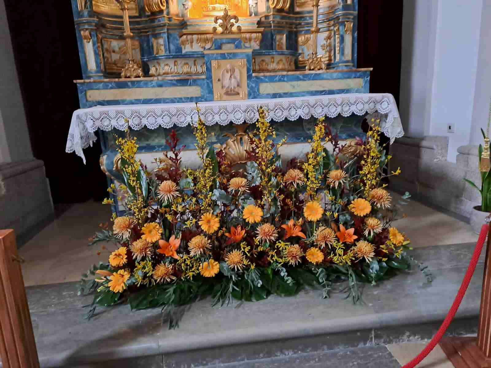 Un altar de iglesia decorado con flores amarillas y naranjas.