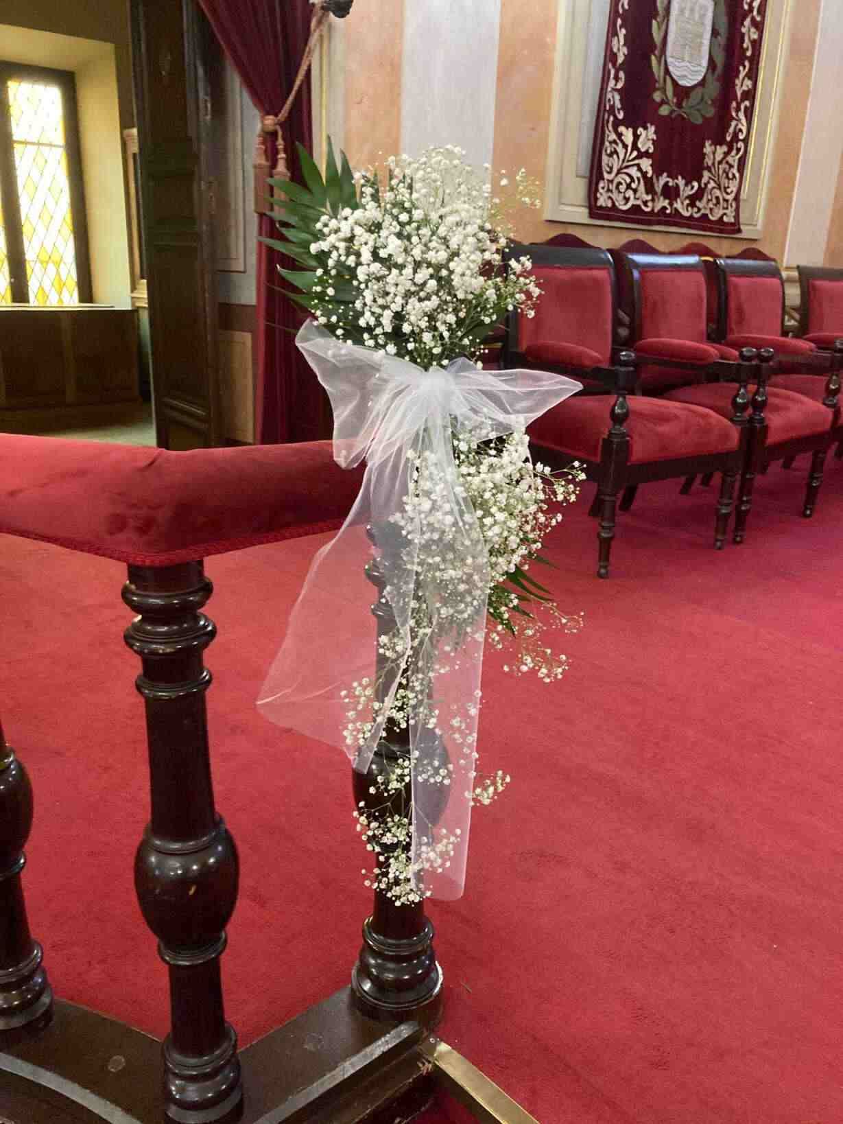 Un ramo de flores de baby's breath se encuentra en un banco de una iglesia.