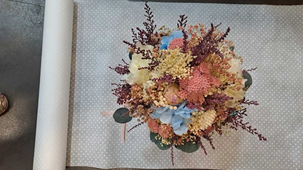 Un ramo de flores secas reposa sobre un trozo de papel sobre una mesa.