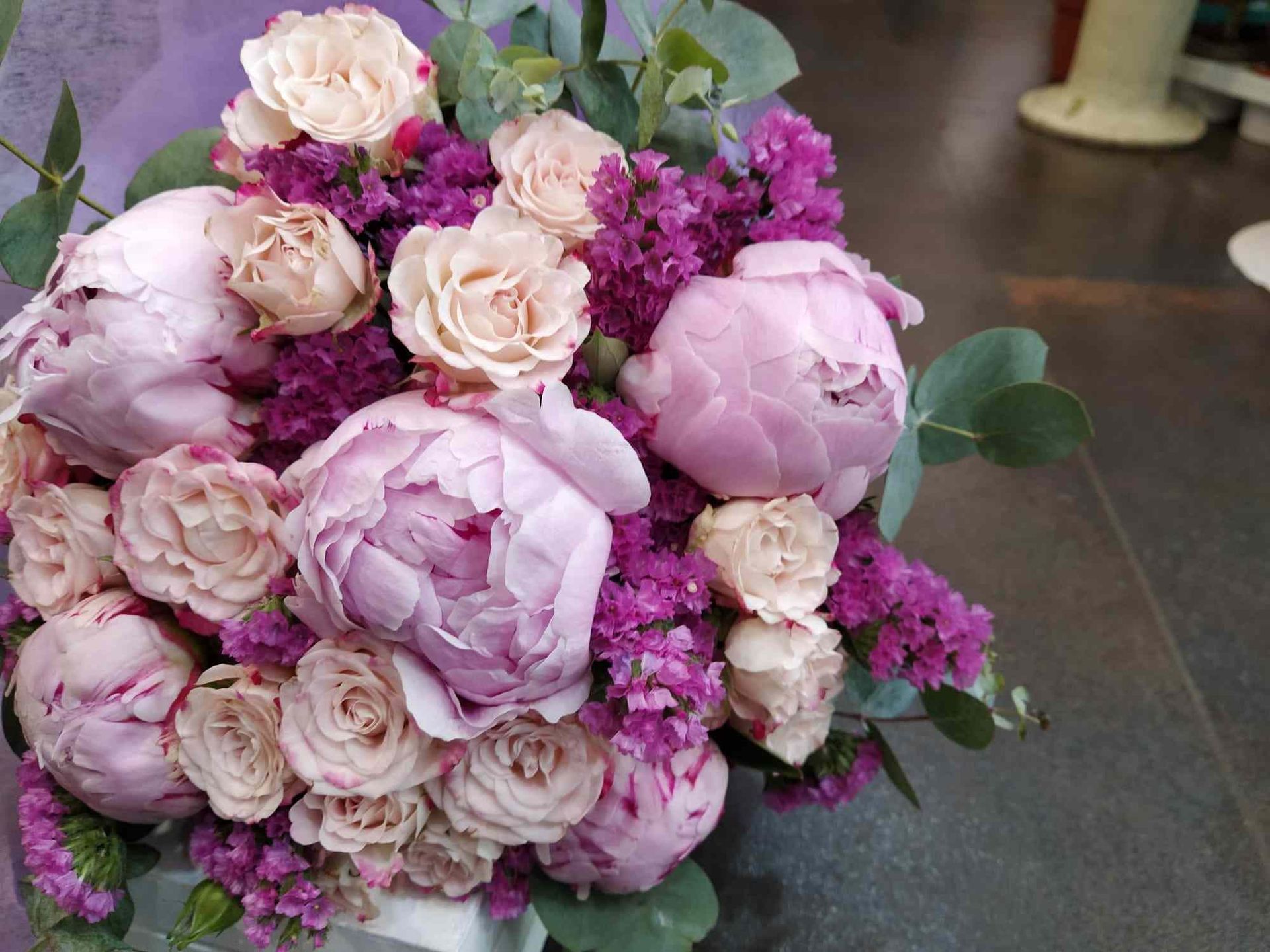 Un ramo de flores rosas y moradas está sobre una mesa.
