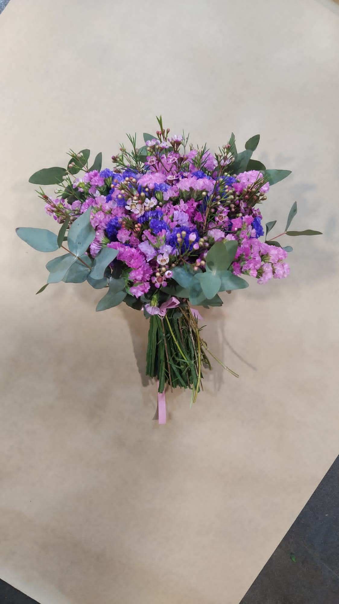 Un ramo de flores de color púrpura y azul está sobre una mesa.