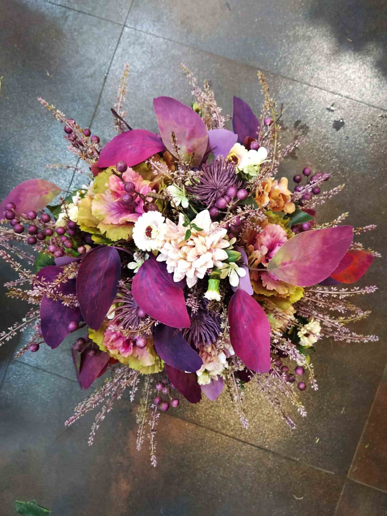 Un ramo de flores de color púrpura se encuentra sobre un suelo de baldosas.