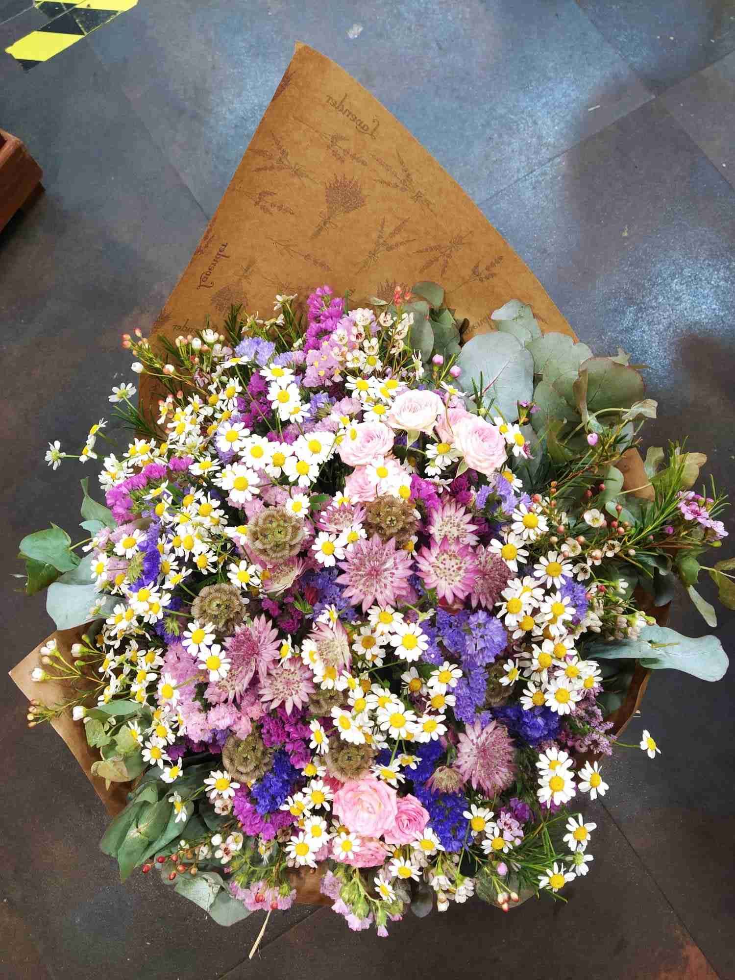 Un ramo de flores está envuelto en papel marrón.