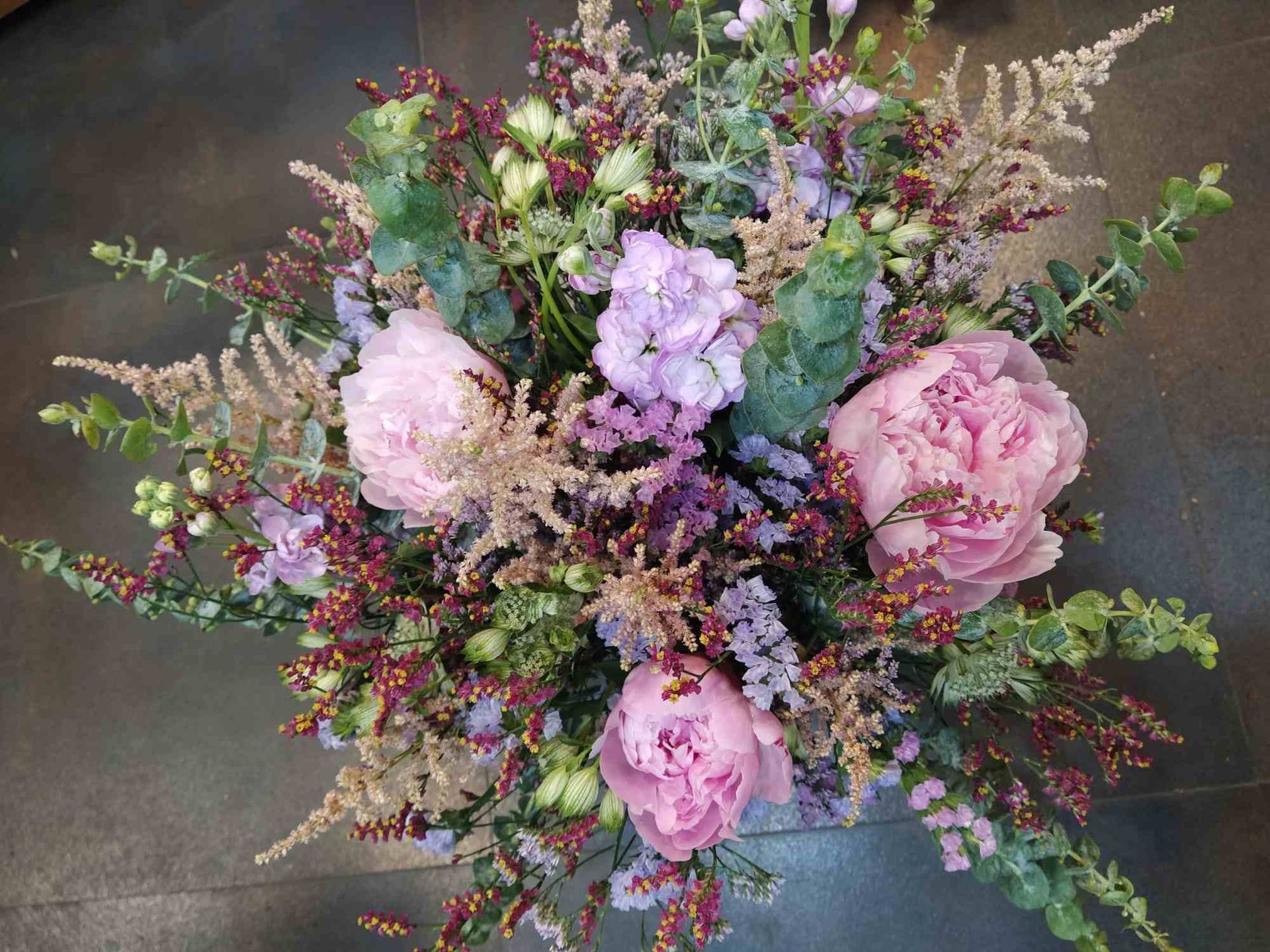 Un ramo de flores rosas y moradas está sobre una mesa.