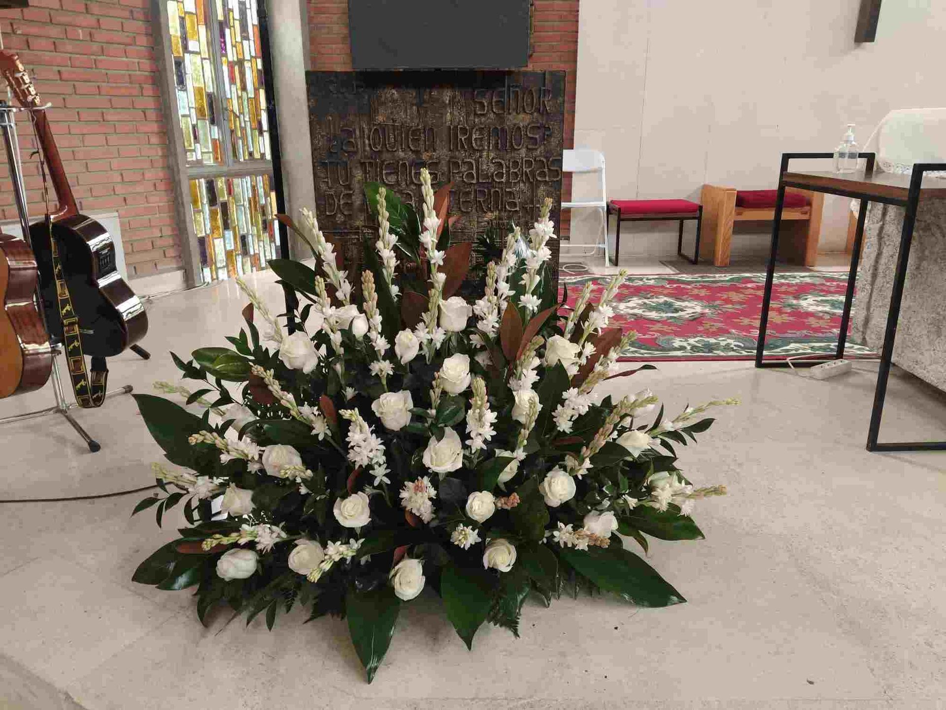 Un gran ramo de flores blancas en una iglesia con una guitarra de fondo.