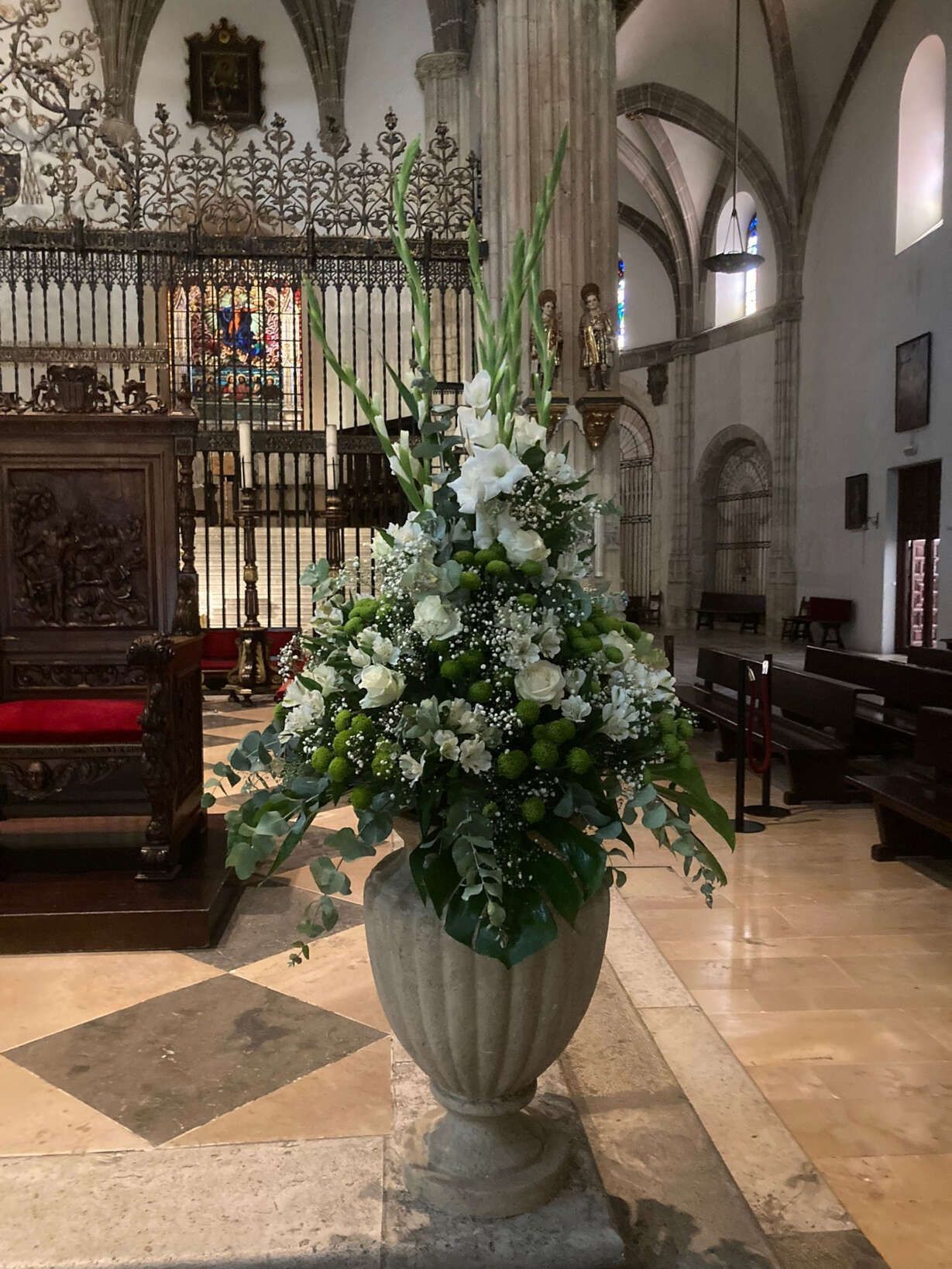 Un jarrón lleno de flores está en el medio de una iglesia.