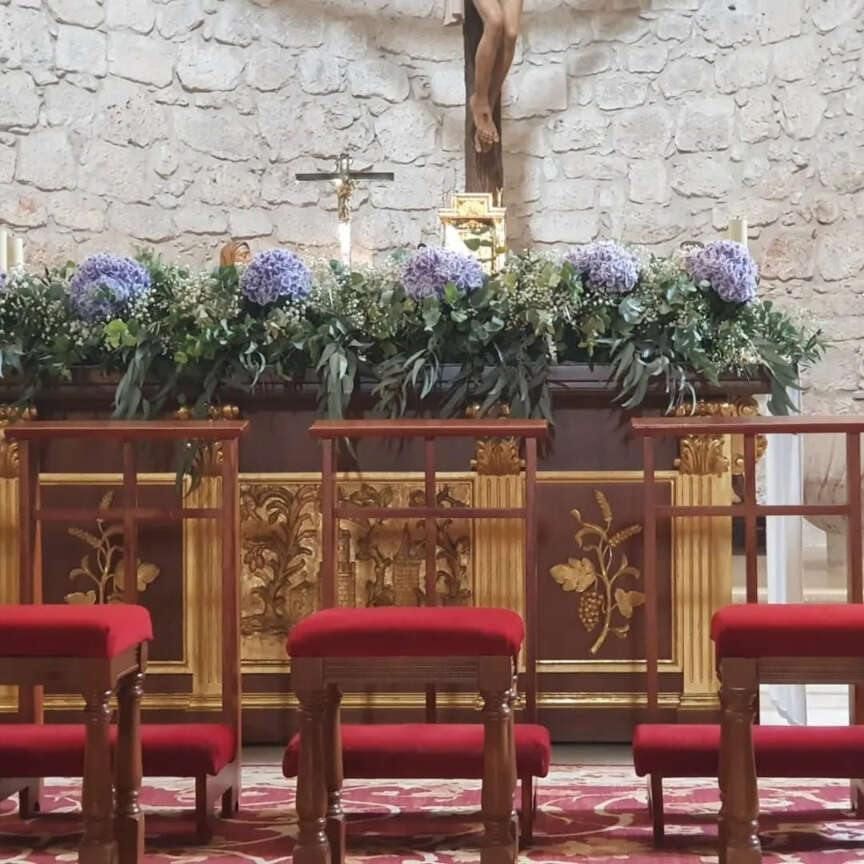 Una iglesia con una cruz y flores en el altar.