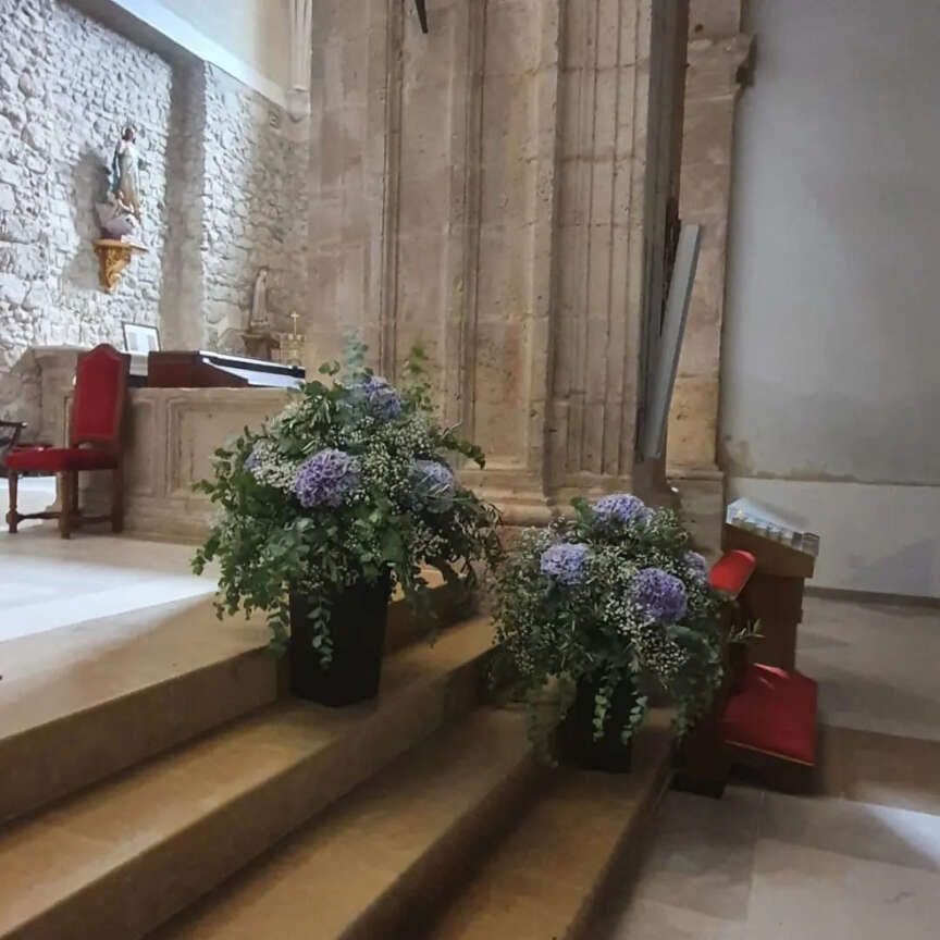 Dos jarrones con flores de color púrpura se encuentran en las escaleras de una iglesia.