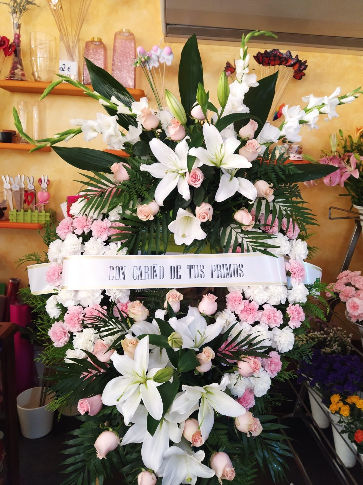 Una corona de flores blancas y rosas con una cinta que dice
