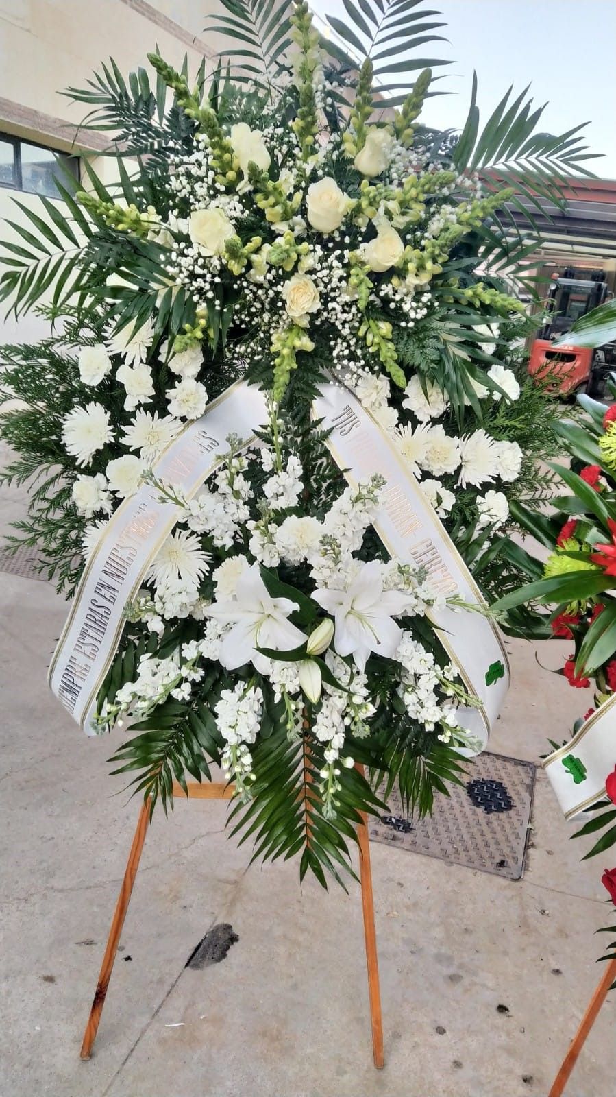 Una corona de flores blancas reposa sobre un soporte de madera.