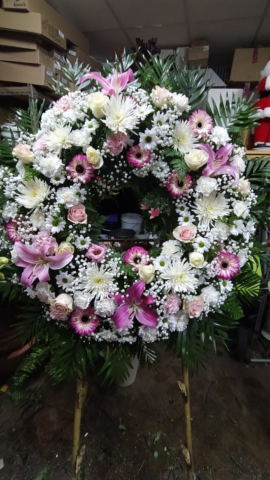 Una corona de flores rosas y blancas reposa sobre un soporte.