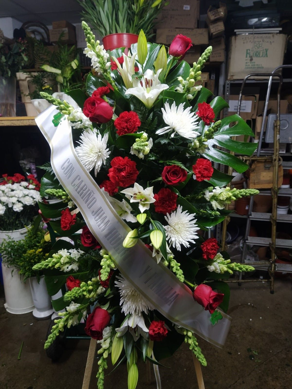 Un ramo de flores rojas y blancas con una cinta blanca que dice