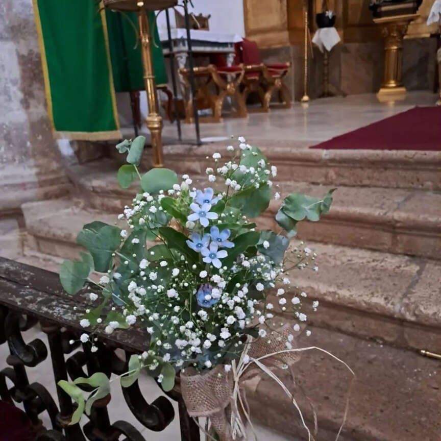 Un ramo de flores de aliento de bebé y azules se encuentra en los escalones de una iglesia.