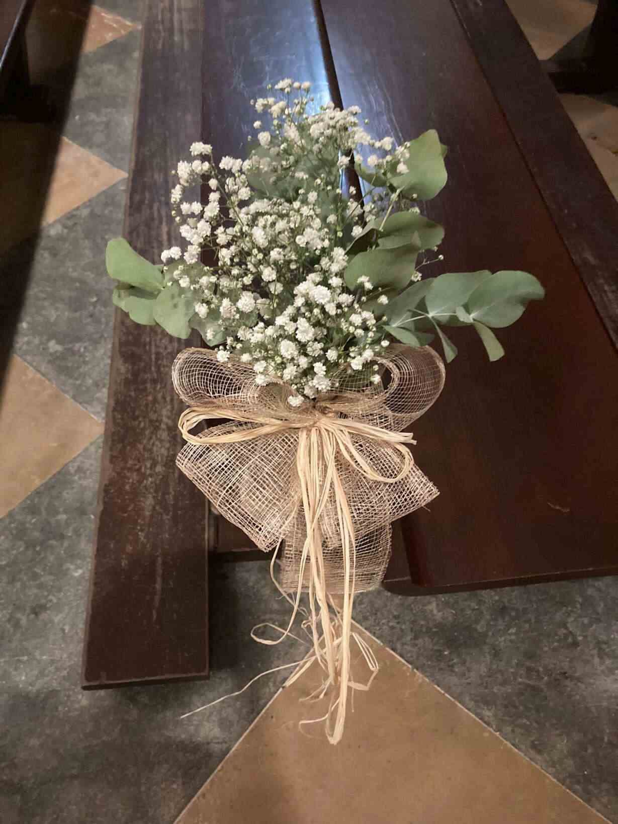 Un ramo de flores de baby's breath se encuentra sobre un banco de madera.