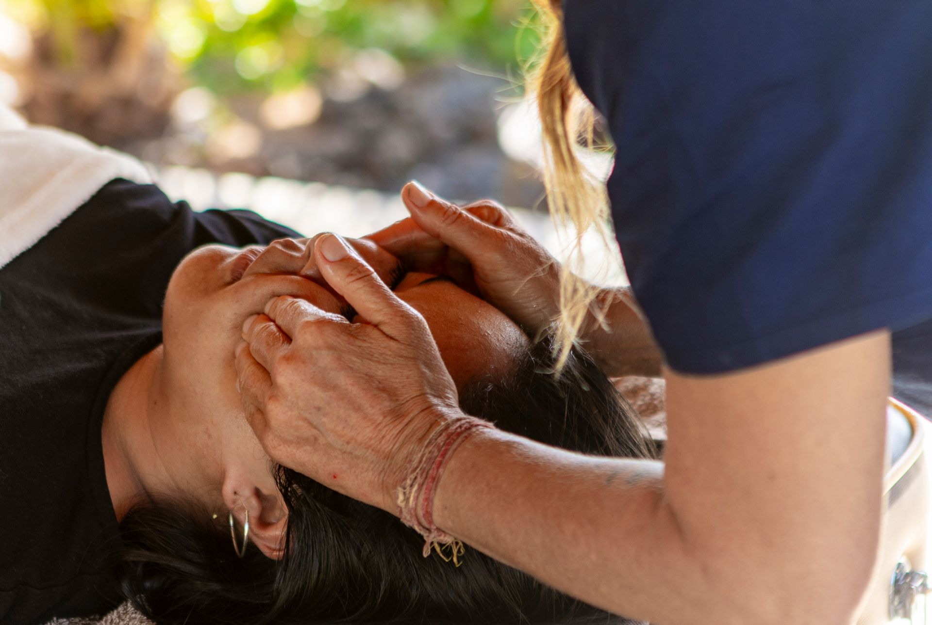 Des mains positionnant délicatement la tête d’une personne pendant une séance de massage.