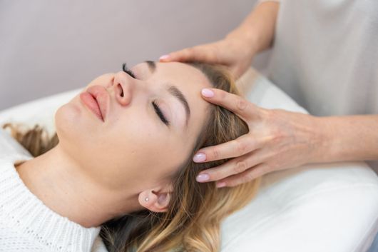 Personne recevant un massage du cuir chevelu, allongée sur un oreiller.