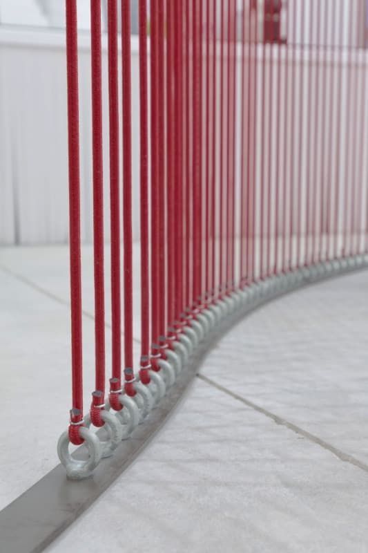 Un primer plano de una cerca de alambre rojo sobre un piso de baldosas.