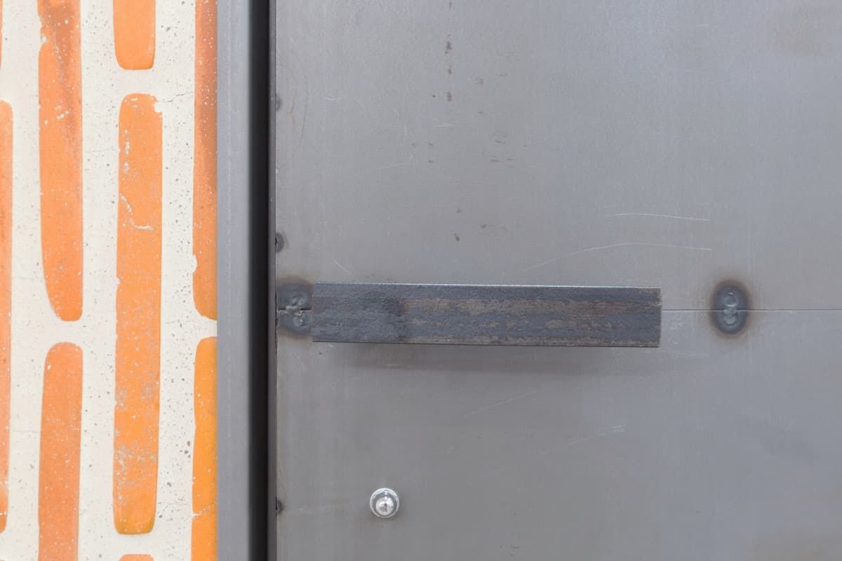 Un primer plano de una manija de puerta de metal en una pared de ladrillos.