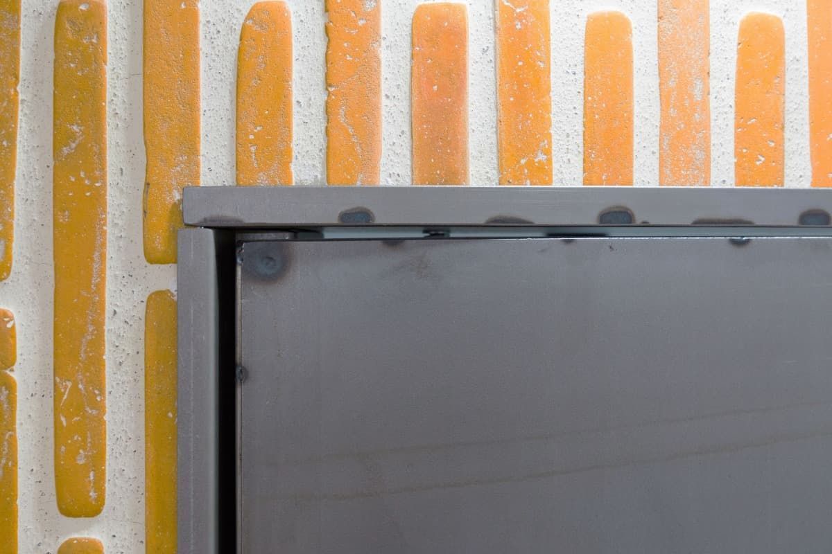 Un primer plano de una puerta de metal en una pared de ladrillos.