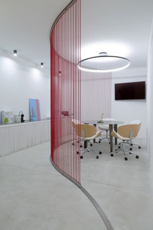 Una habitación con una mesa y sillas y una cortina roja entre ellas.