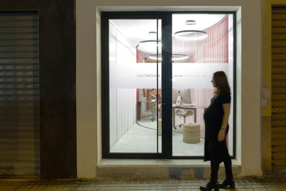 Una mujer con un vestido negro está parada frente a una puerta de vidrio.