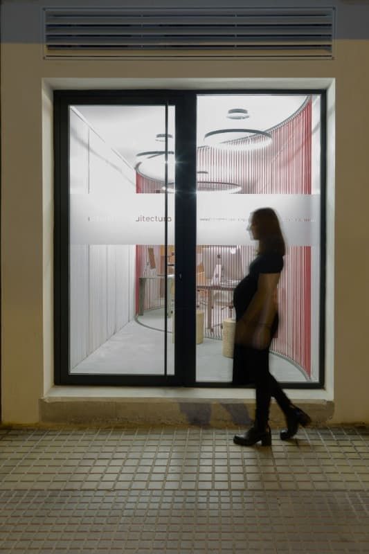 Una mujer camina frente a una tienda con una puerta corrediza de vidrio.