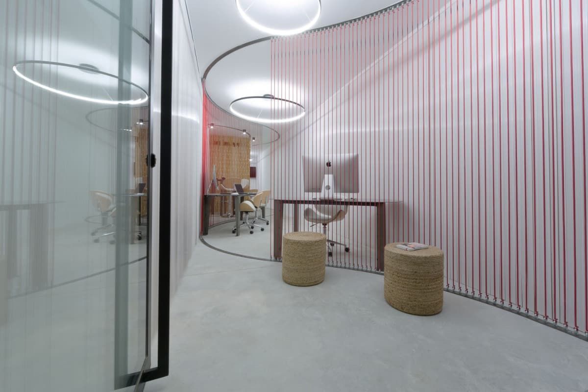 Una habitación con un escritorio y sillas y una pared rosa.