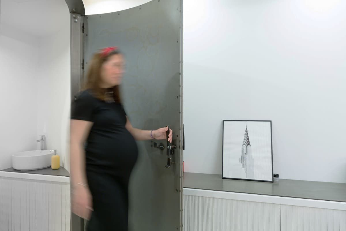 Una mujer embarazada está abriendo una puerta en un baño.