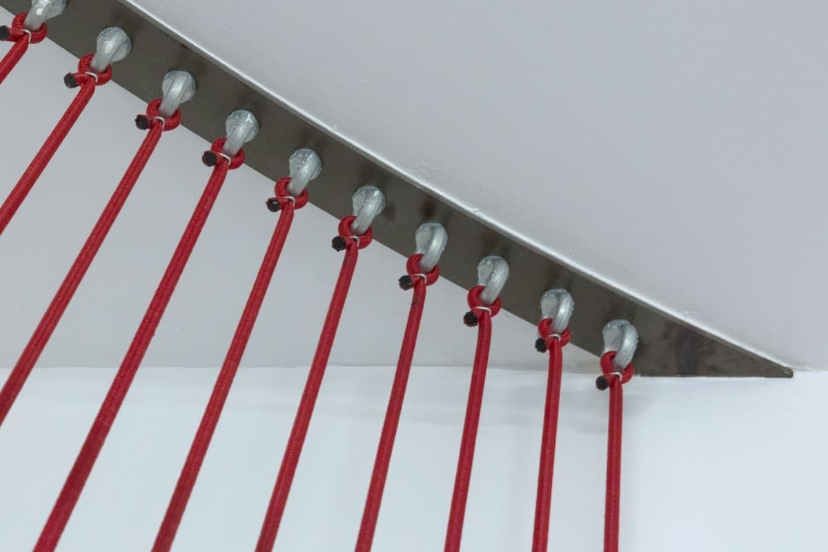 Un montón de palos rojos cuelgan en una pared blanca