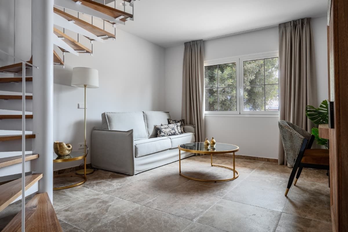 Una sala de estar con una escalera de caracol, un sofá, una mesa de café y una lámpara.