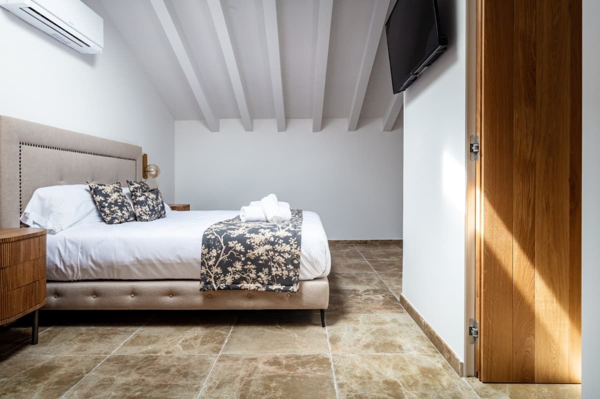 Un dormitorio con una cama king size y un televisor de pantalla plana en la pared.