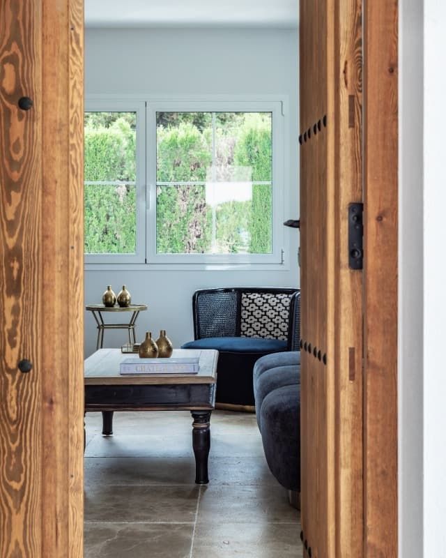 Una puerta de madera abierta a una sala de estar con una mesa y sillas.