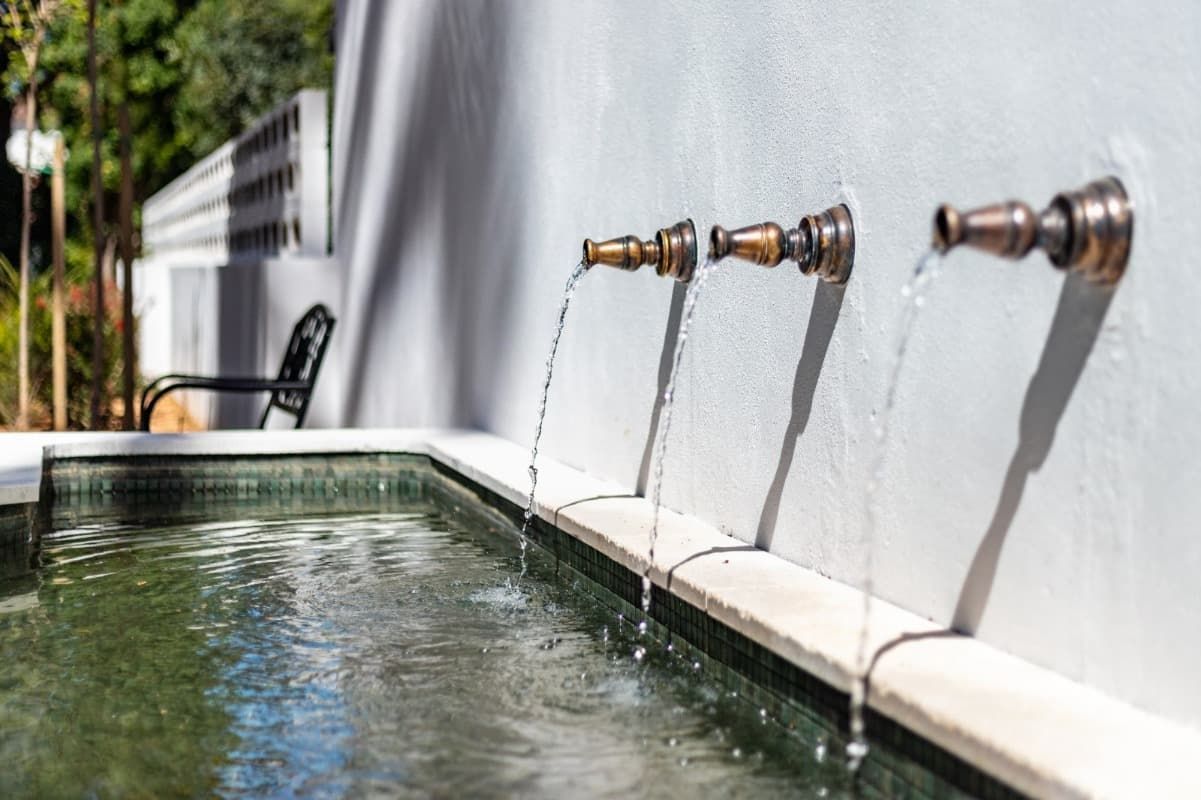 Una piscina con tres grifos que arrojan agua en ella.