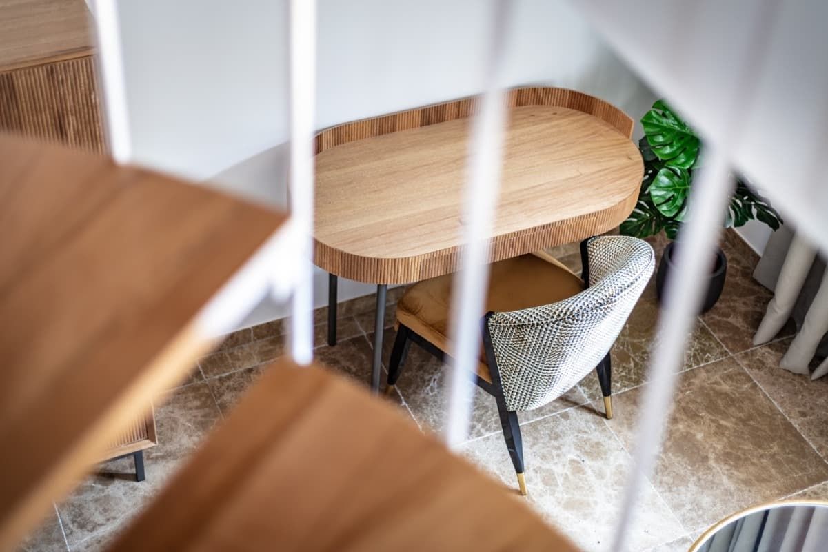 Un escritorio y una silla de madera en una habitación con escaleras de caracol.